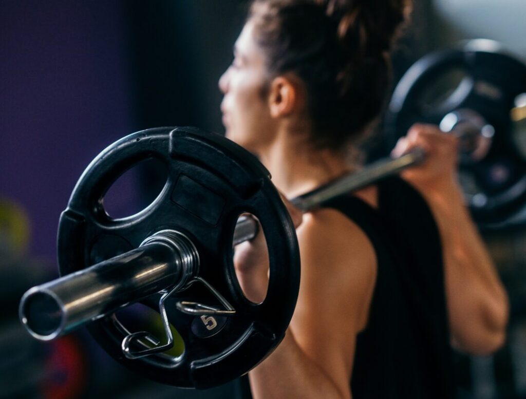 woman performing barbell strength training exercise in gym
