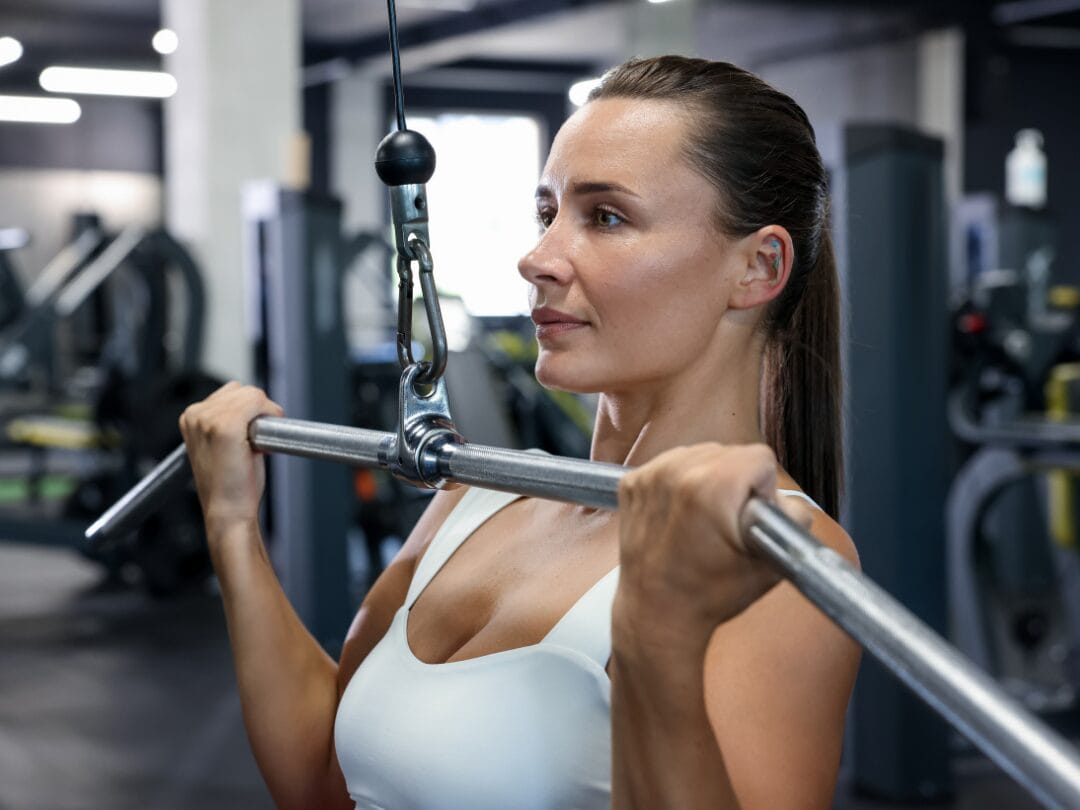 Woman doing a lat pulldown with personal trainer